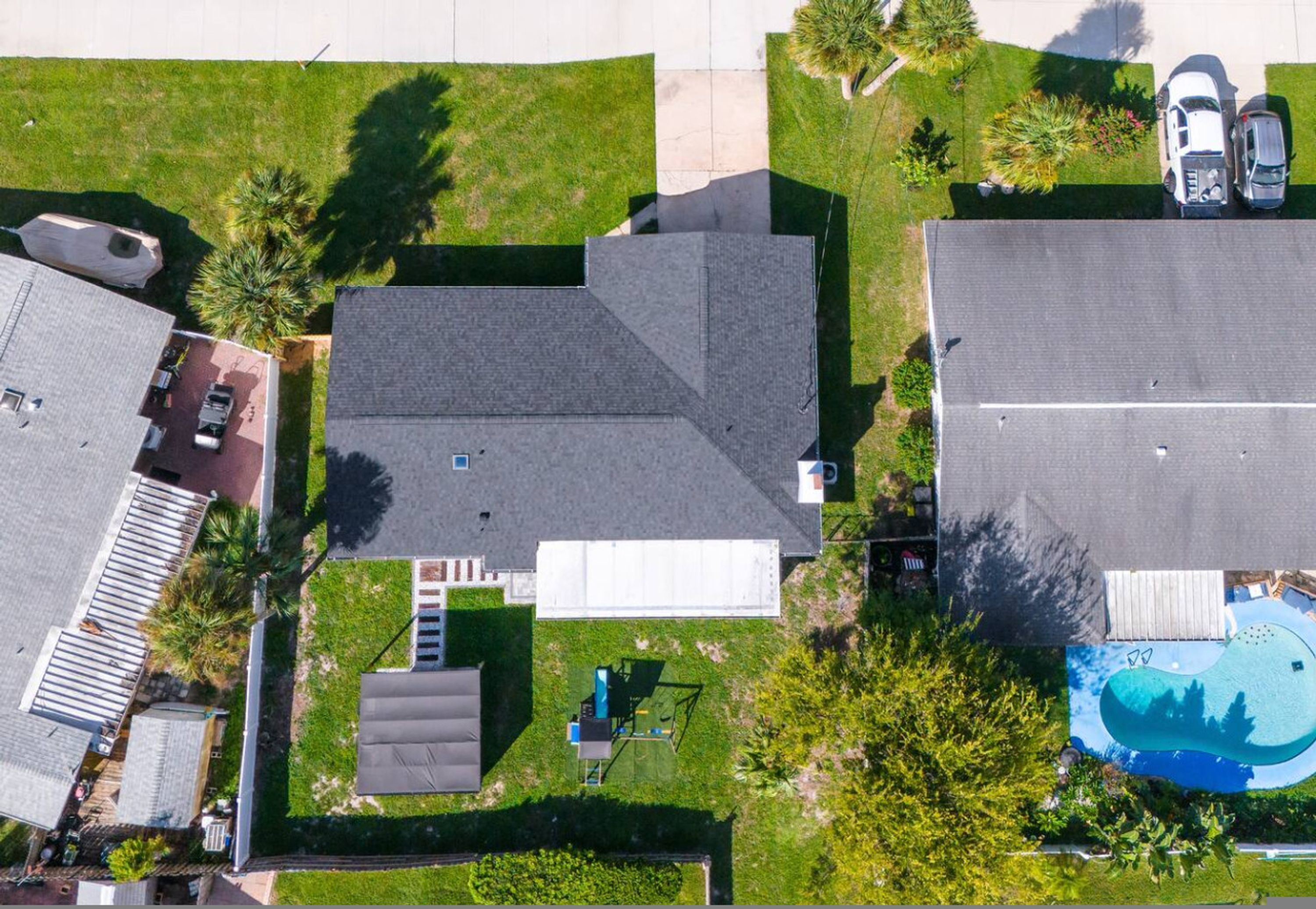 Vista aerea di una zona residenziale con diverse case, una piscina e un’area di parcheggio.