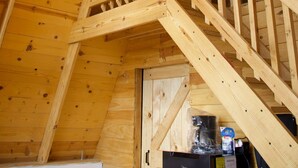 Un intérieur en bois avec un escalier, un luminaire suspendu et un réfrigérateur.