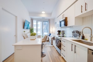 Eine moderne Küche mit weißen Schränken, einer zentralen Kochinsel, einer Mikrowelle und einer backsplash mit Fischgrätenmuster.