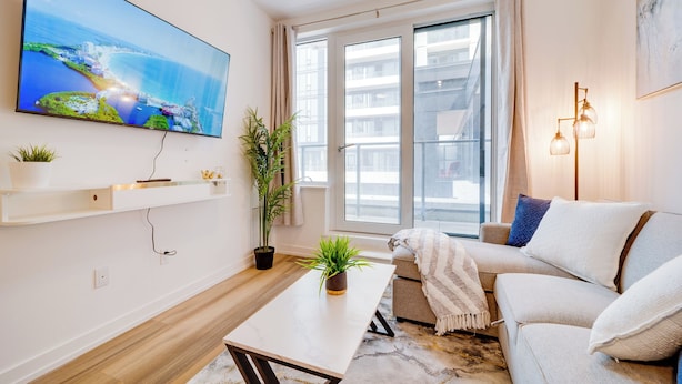 Un salon moderne avec un grand téléviseur à écran plat, un canapé, une table basse et une plante en pot.