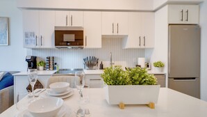 Une cuisine moderne avec des armoires blanches, un four encastré et un réfrigérateur en acier inoxydable.
