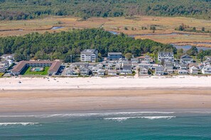 A coastal residential area with beachfront properties, a swimming pool complex, and a dense forested background. - Little Miss Cottages - 173 House (Old Orchard Beach)