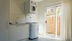 A laundry room with a washing machine, dryer, and a small cabinet. - Cedar Sands Hideaway - 3BRM Home (Gold Coast)