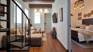 Un intérieur moderne comprenant un escalier, un espace de vie avec un canapé et une table basse, et une chambre à coucher avec un lit et une table de chevet.