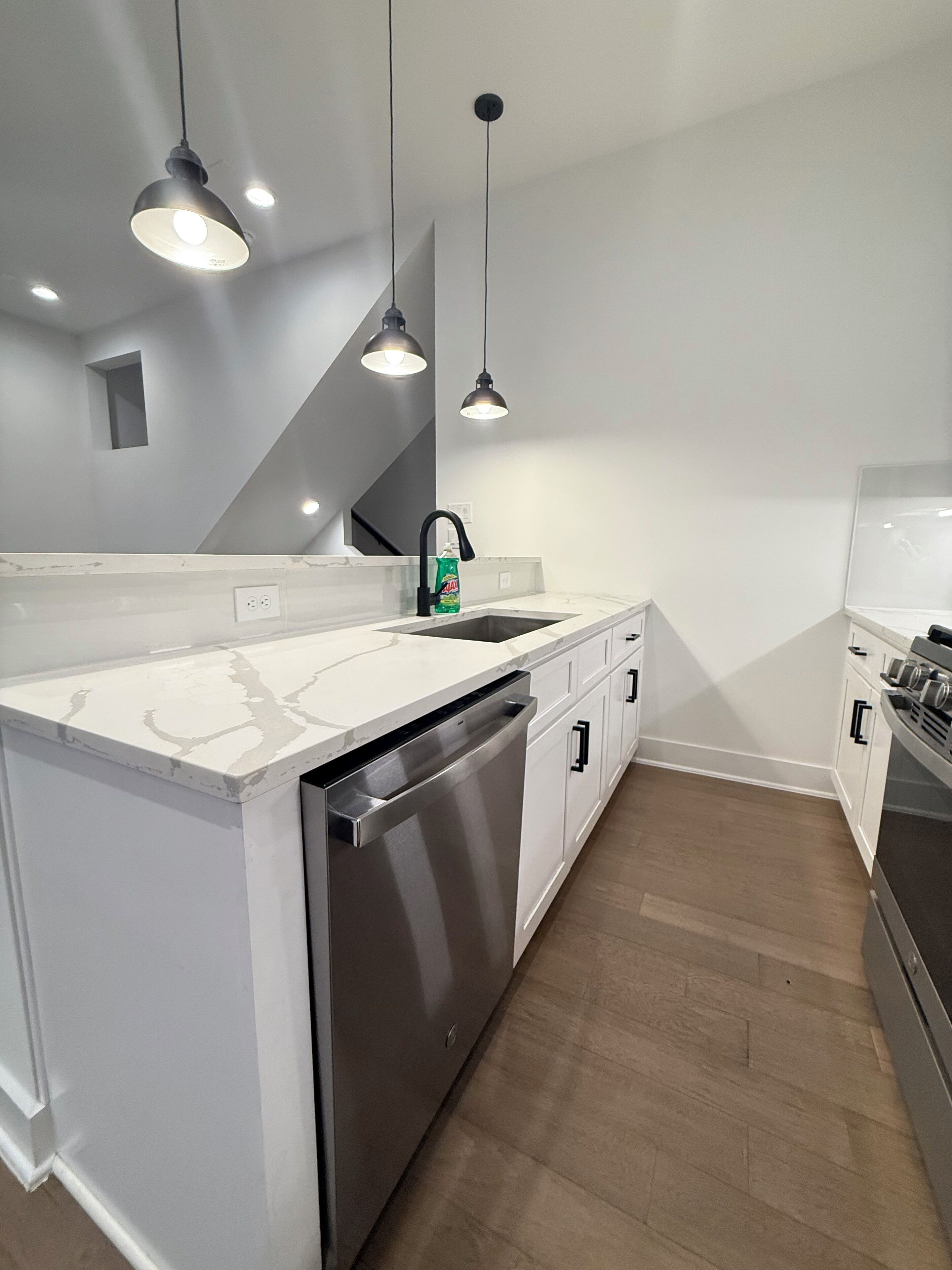 A modern kitchen with a large island, stainless steel appliances, and pendant lighting.