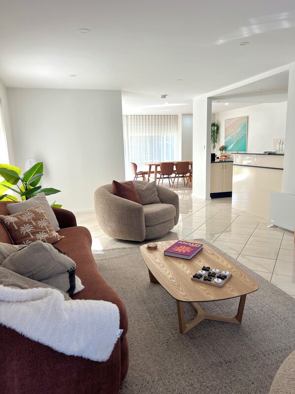 A modern living room with a brown sofa, a beige armchair, and a wooden coffee table.