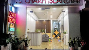 The entrance of Charm Island Hotel with a reception desk, potted plants, and a clear glass door. - Cat Ba Charm Island Hotel (Hai Phong)