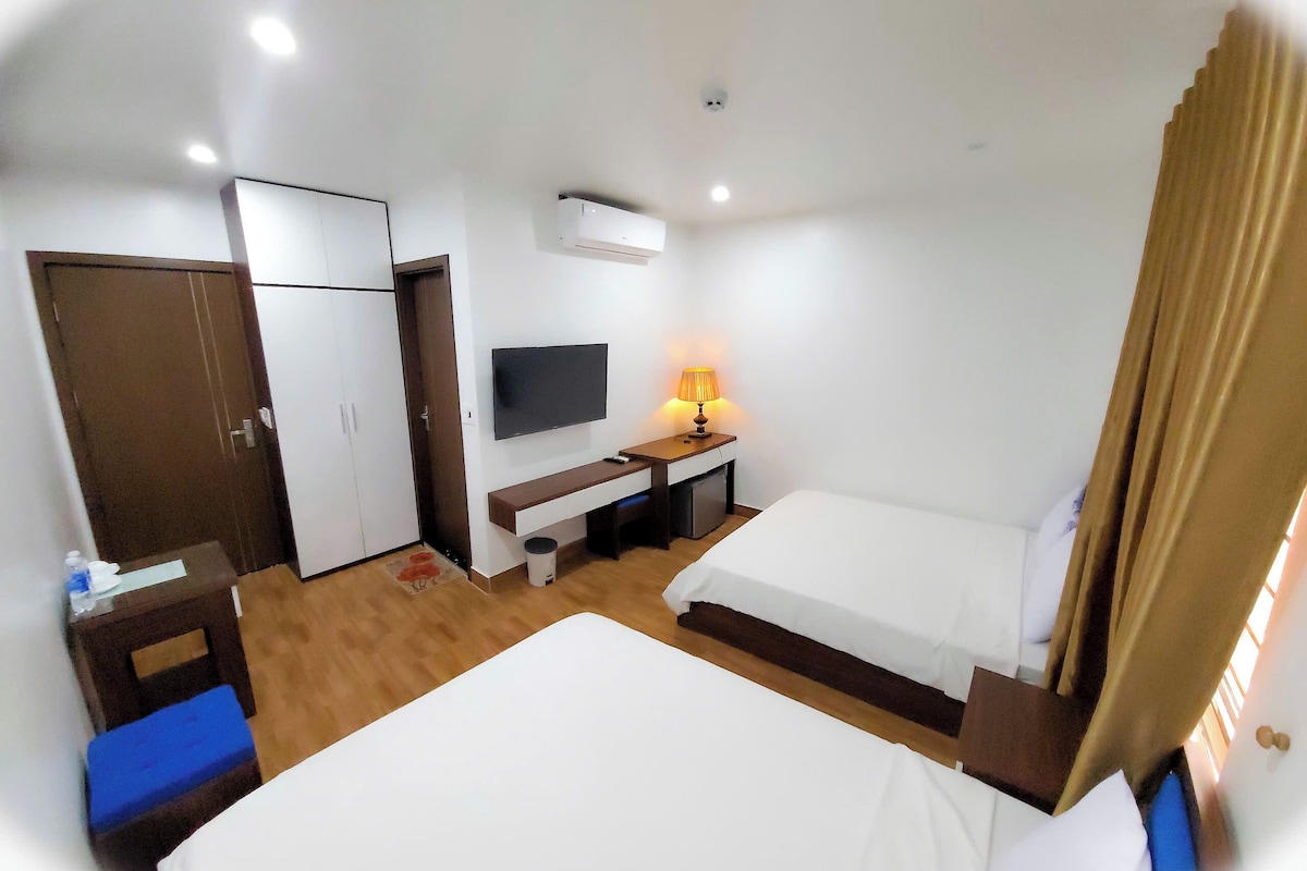 Une chambre d’hôtel comprenant un lit, un bureau avec une lampe, une télévision et une armoire.