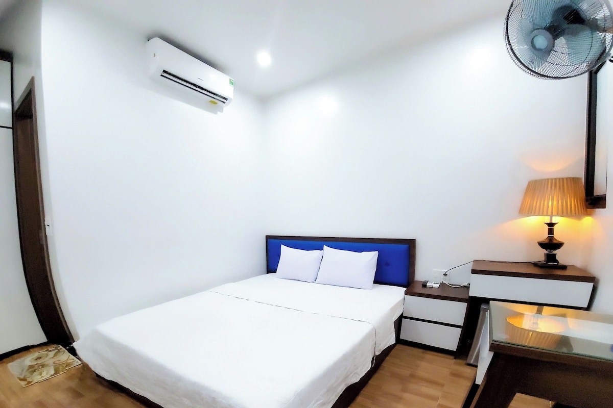 Une chambre d’hôtel équipée d’un lit, d’une table de chevet, d’une lampe et d’un climatiseur.