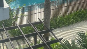 Una piscina rodeada por una valla de madera, con una estructura de piedra cerca y abundante vegetación al fondo.