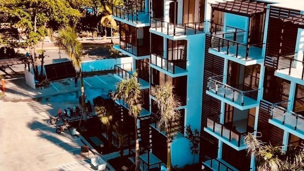 Un hotel de varios pisos con balcones, piscina y vista al océano.