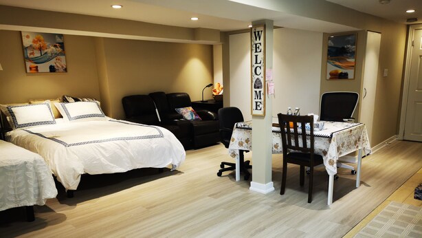 A hotel room with two beds, a sofa, a table with chairs, and a 'WELCOME' sign.