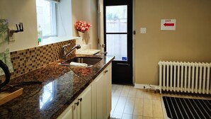 A kitchen with a granite countertop, a sink, a window, and a door leading outside.