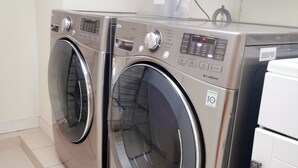 A laundry room with two front-loading washing machines and a small white refrigerator.