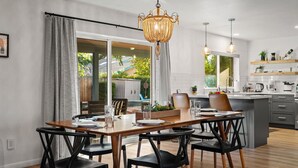 Cocina moderna con comedor, que incluye una isla grande, iluminación colgante y vistas al exterior.