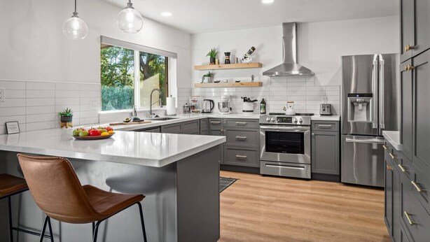 Una cocina moderna con una isla central, electrodomésticos de acero inoxidable y un ventanal que proporciona luz natural.