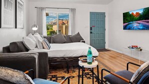 Una habitación moderna y bien iluminada con una cama, un sofá, una mesita y un televisor.