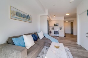 Ein modernes Wohnzimmer mit einer Eckcouch, einem Marmortisch und einer Küche im Hintergrund.