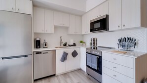 A modern kitchen with white cabinetry, stainless steel appliances, and a microwave above the stove.