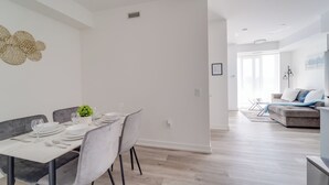 A modern dining area with a table set for four, a grey sofa, and a minimalist decor.