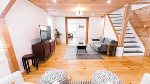 Un grand salon avec un plancher en bois, un canapé, une table basse et un téléviseur.