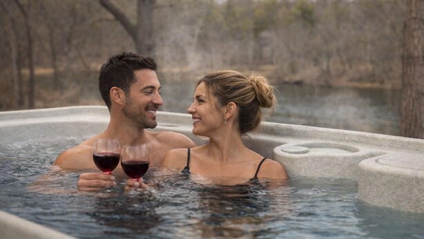 Un couple dans un bain à remous, avec un paysage naturel en arrière-plan.