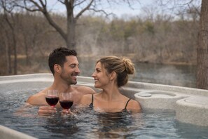 A couple in a hot tub with a natural landscape in the background.