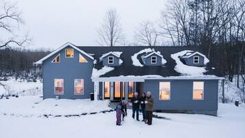 Een huis met twee verdiepingen, een sneeuwbedekte kap en een voortuin met veranda.