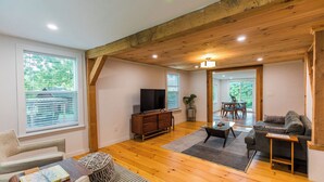 Un salon spacieux doté d’un plancher en bois, d’un téléviseur, d’un canapé et d’un coin repas avec une table et des chaises.