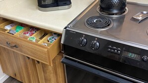 Una kitchenette con una cafetera Keurig, un fogón y un cajón con cápsulas de café.