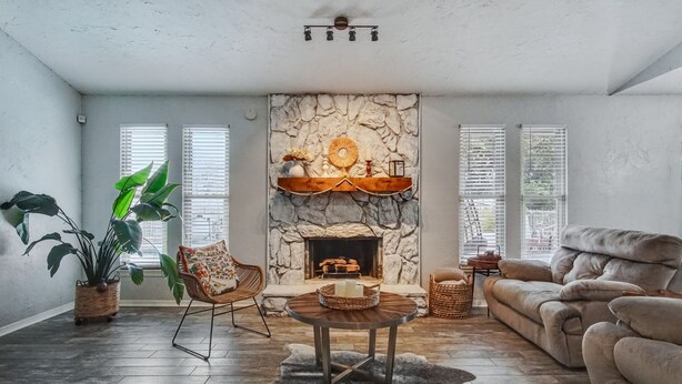 Una sala de estar acogedora con chimenea de piedra, un sofá cómodo, una mesa de comedor y una planta grande en maceta.