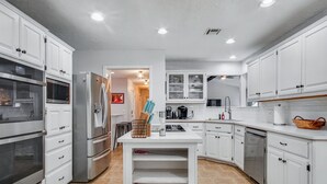 Una cocina moderna con armarios blancos, electrodomésticos de acero inoxidable y una isla central.