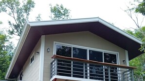 A two-story house with a red garage door and a balcony with metal railings. - Magnolia Farm Suite
      Giffin House
       Pet friendly (San Isidro de El General)