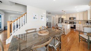 Una cocina amplia con armarios de madera, un comedor con mesa de vidrio y una escalera que lleva a otro nivel.