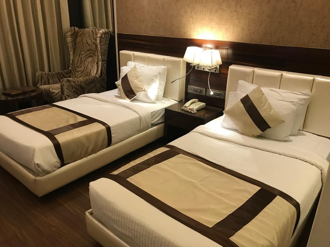 Ein Hotelzimmer mit zwei Betten, jeweils mit Kopfstütze, Nachttischen, Lampen und einem Telefon.