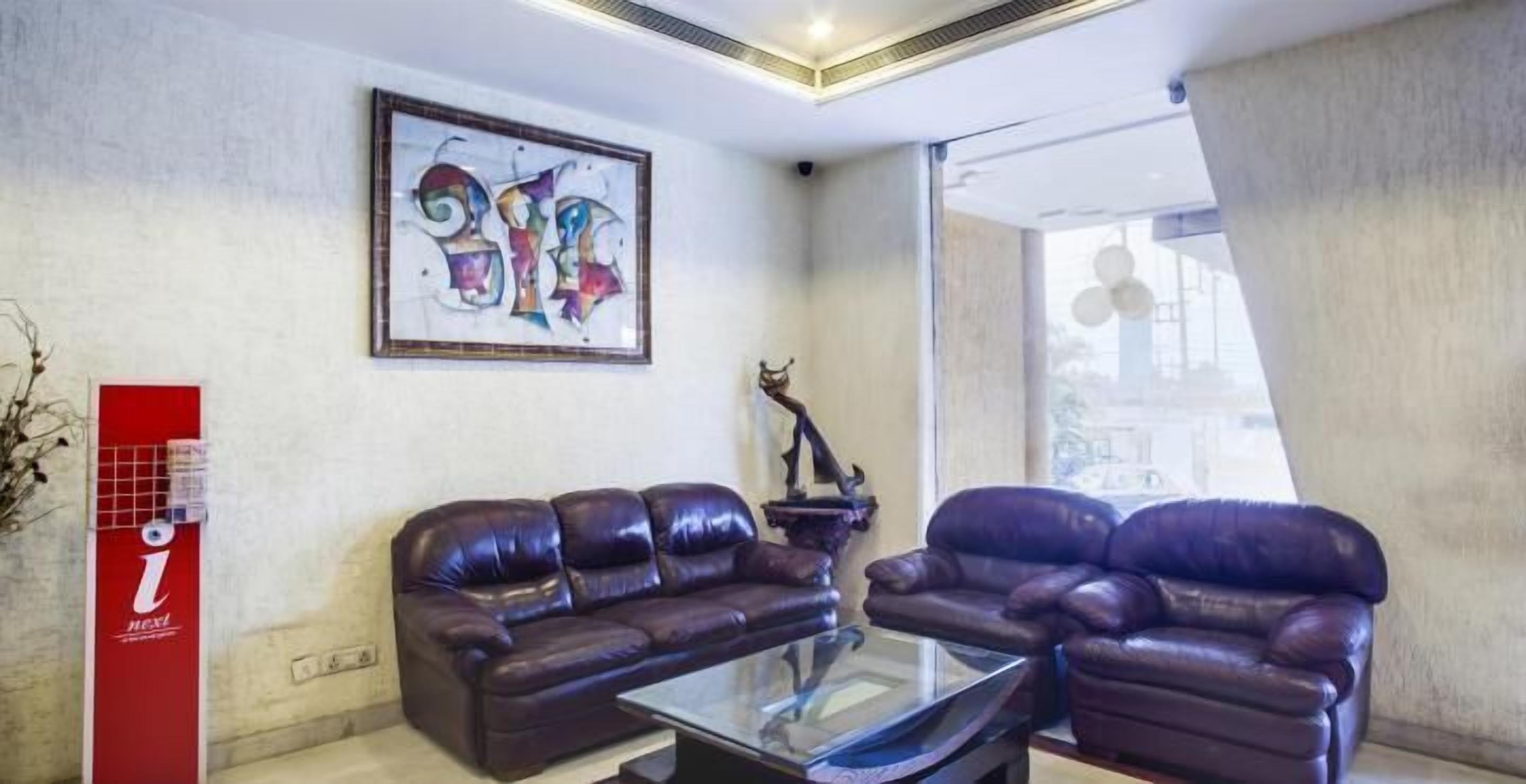 A modern living room with two leather sofas, a glass coffee table, and a colorful abstract painting on the wall.