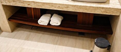 A bathroom with two sinks, a towel rack with towels, a toilet, and a trash can.