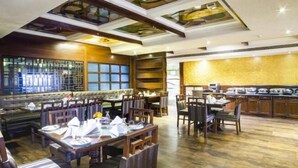 Un restaurant doté de mobilier en bois, d’un bar et d’une cuisine visible à travers une paroi en verre.