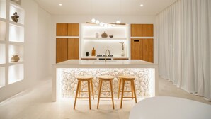 Uma cozinha moderna com ilha central, armários de madeira e parede decorativa em pedra.