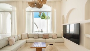 Uma sala de estar moderna com um amplo sofá modular, uma mesa de centro e uma televisão de tela plana presa à parede.