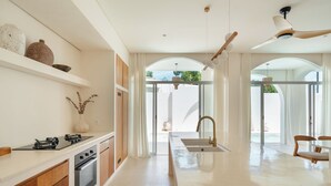 Cozinha moderna com ilha central, forno embutido e uma grande janela que proporciona luz natural.