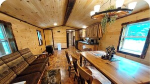 Interior de madera con comedor, sofá y cocina.