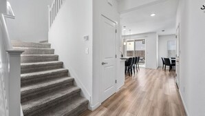 Un intérieur moderne comprenant un escalier, un coin repas et une cuisine.