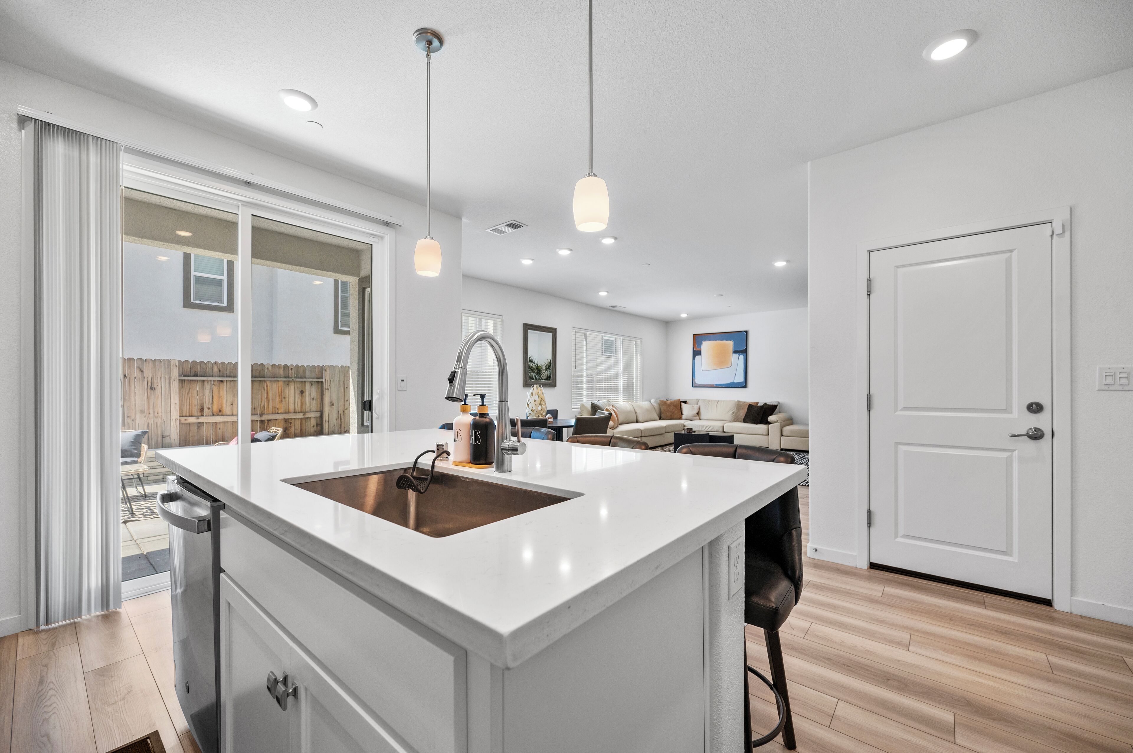 A modern kitchen with a large island, white cabinetry, and pendant lighting.