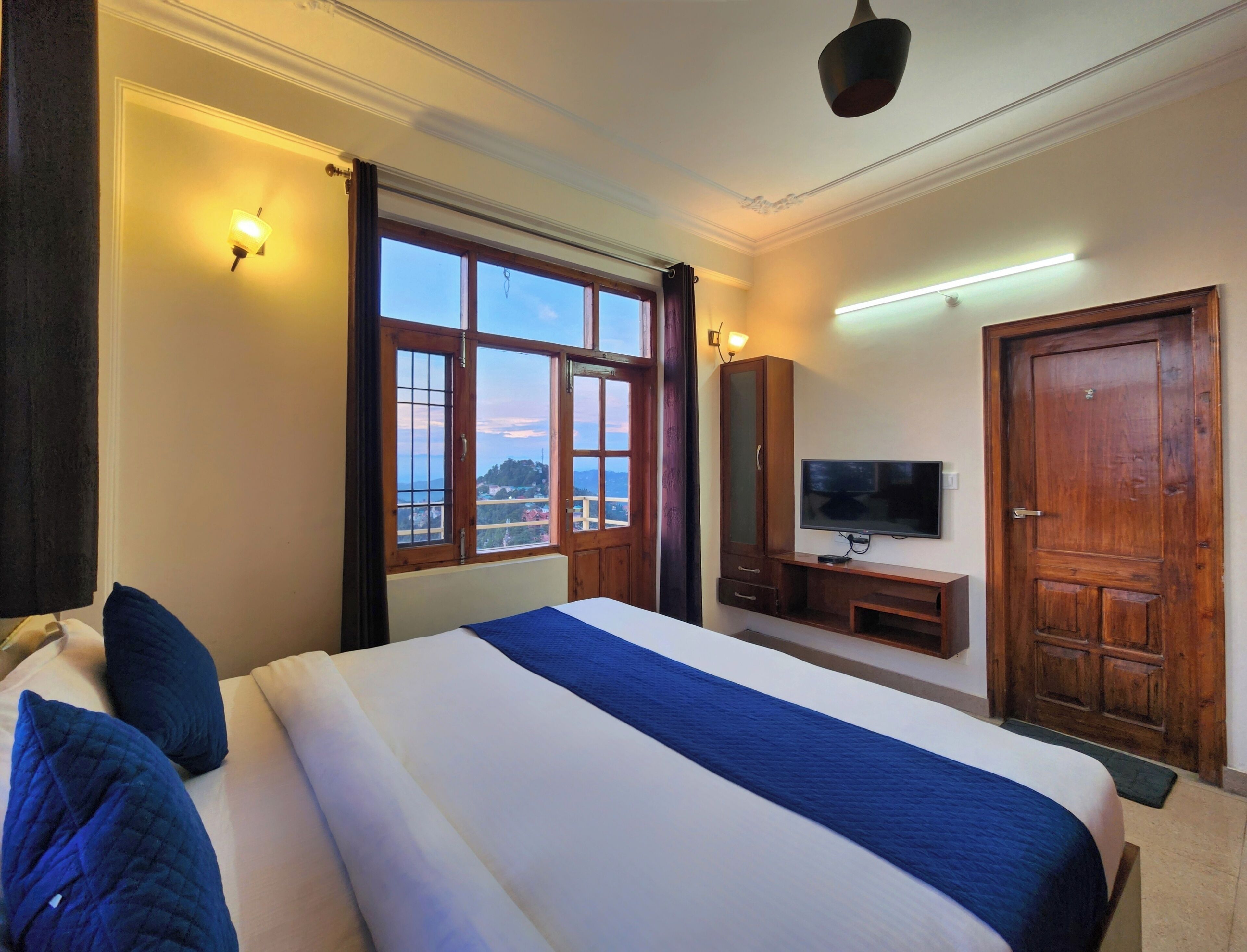 Une chambre d’hôtel avec un grand lit, une télévision, une armoire et une vue sur l’extérieur.