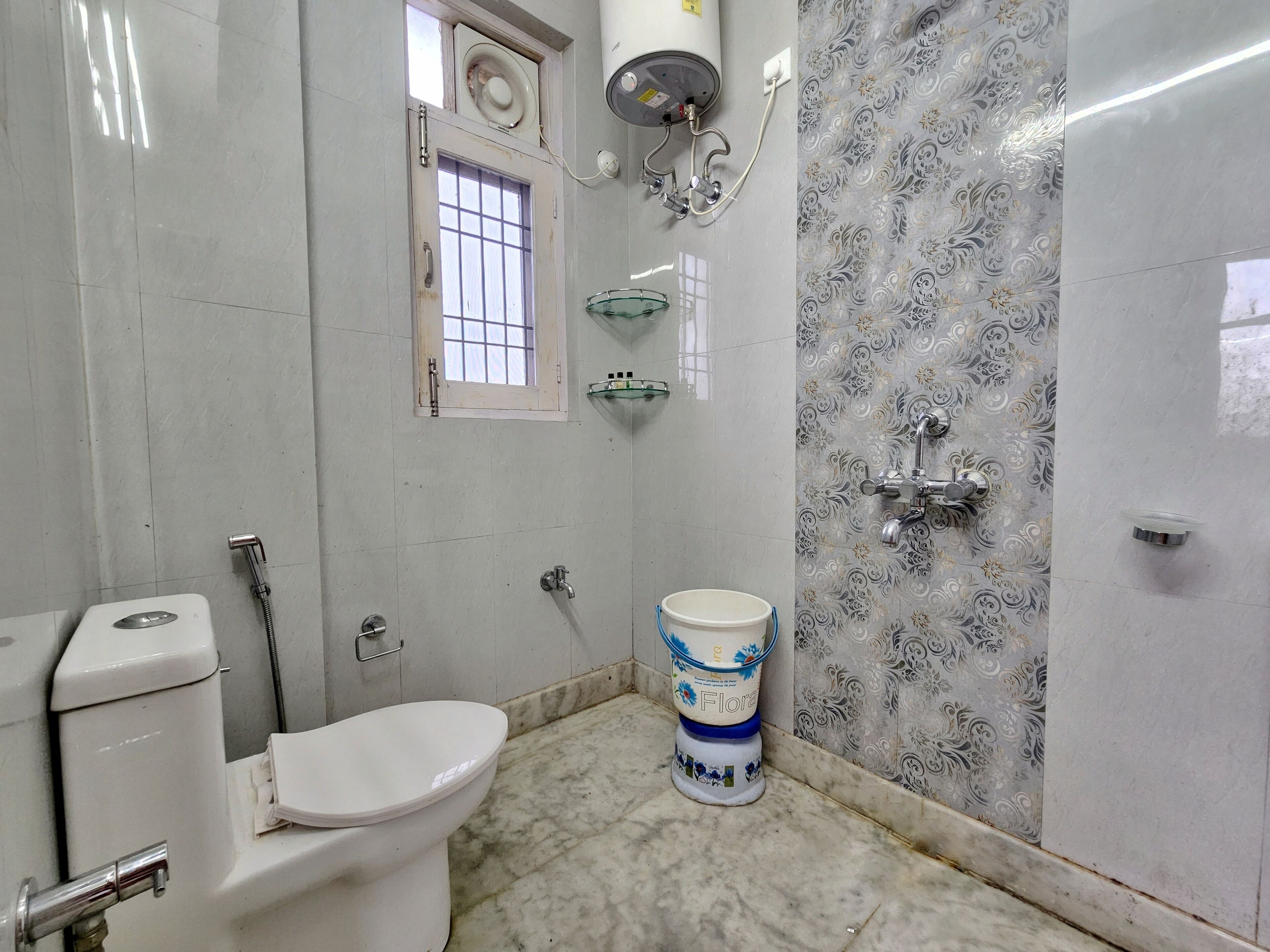 A bathroom with a toilet, a shower, a sink, and a decorative bucket.