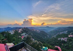 Un paysage montagneux avec un village situé au pied des montagnes, caractérisé par des maisons à étages et offrant une vue imprenable sur le coucher de soleil.