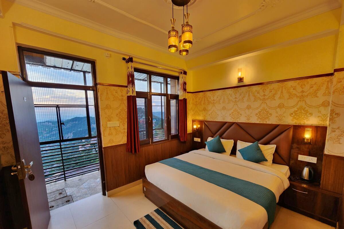 A hotel room with a large bed, wooden headboard, and a view through the window.