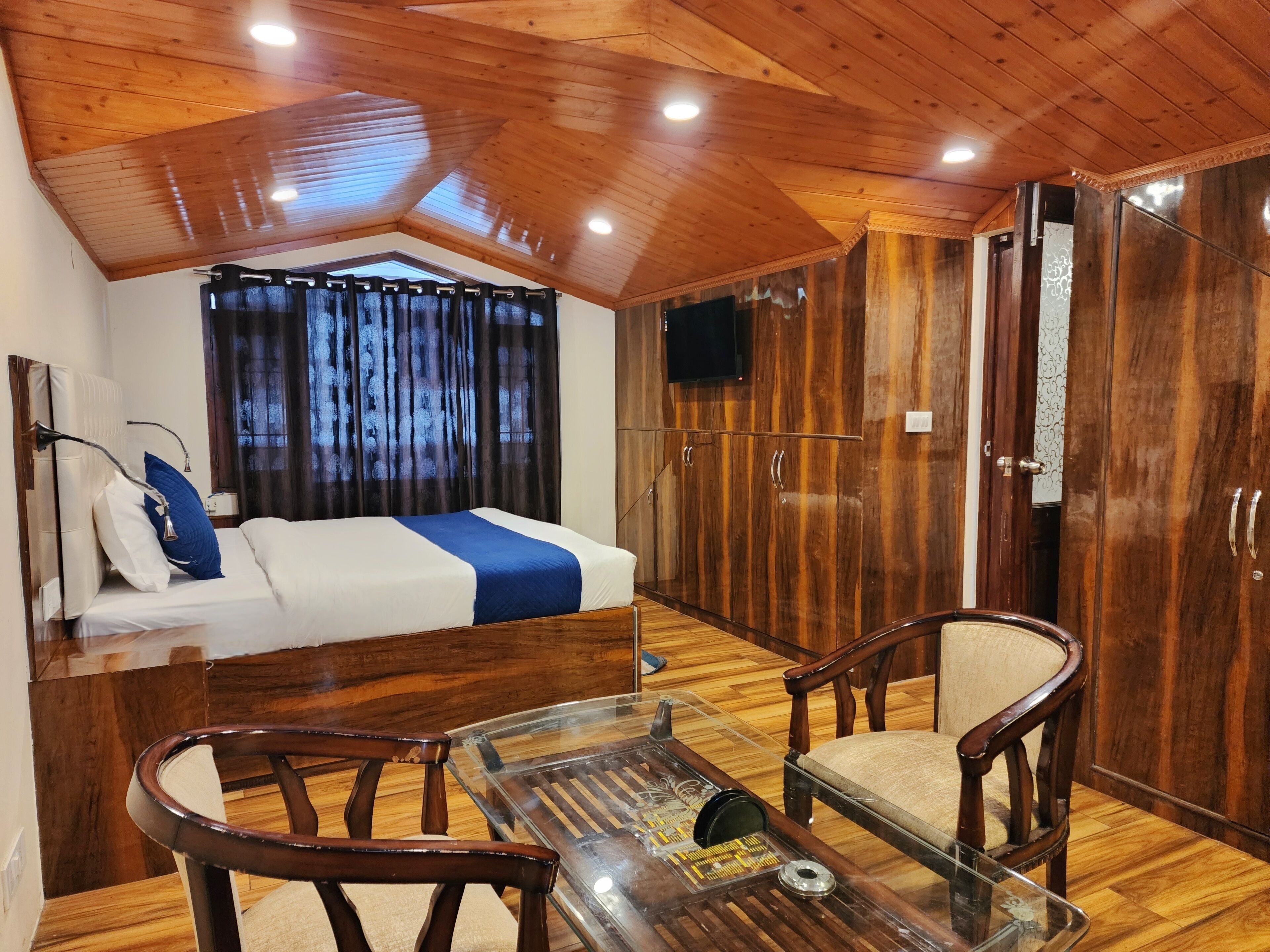 A bedroom with a bed, wooden wardrobe, and a TV.