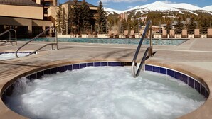 Un bain à remous avec vue sur la montagne et un espace piscine doté de chaises longues.